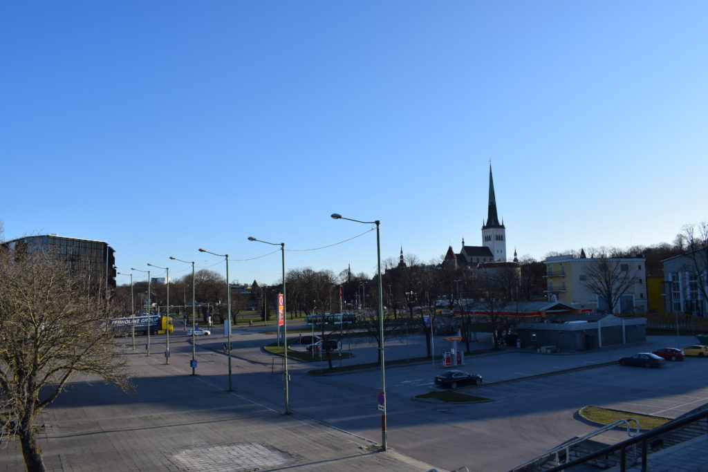 Taustalla siintää kirkon torni. Edessä tyhjiä parkkipaikkoja.