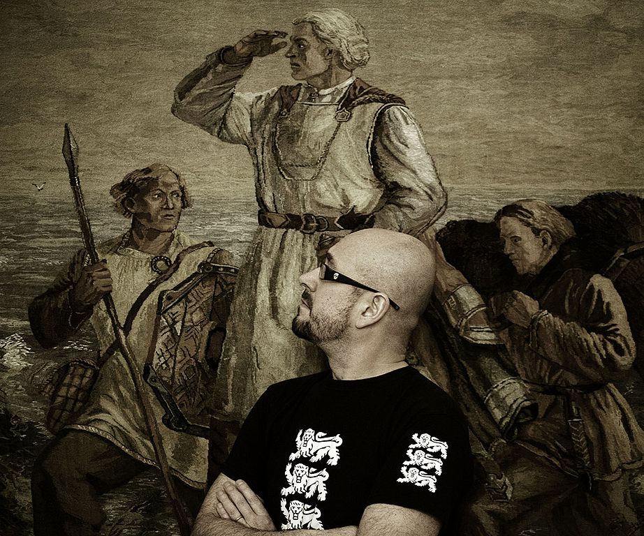 Runoilija Asko Künnap mustassa t-paidassa, taustalla vanha maalaus.