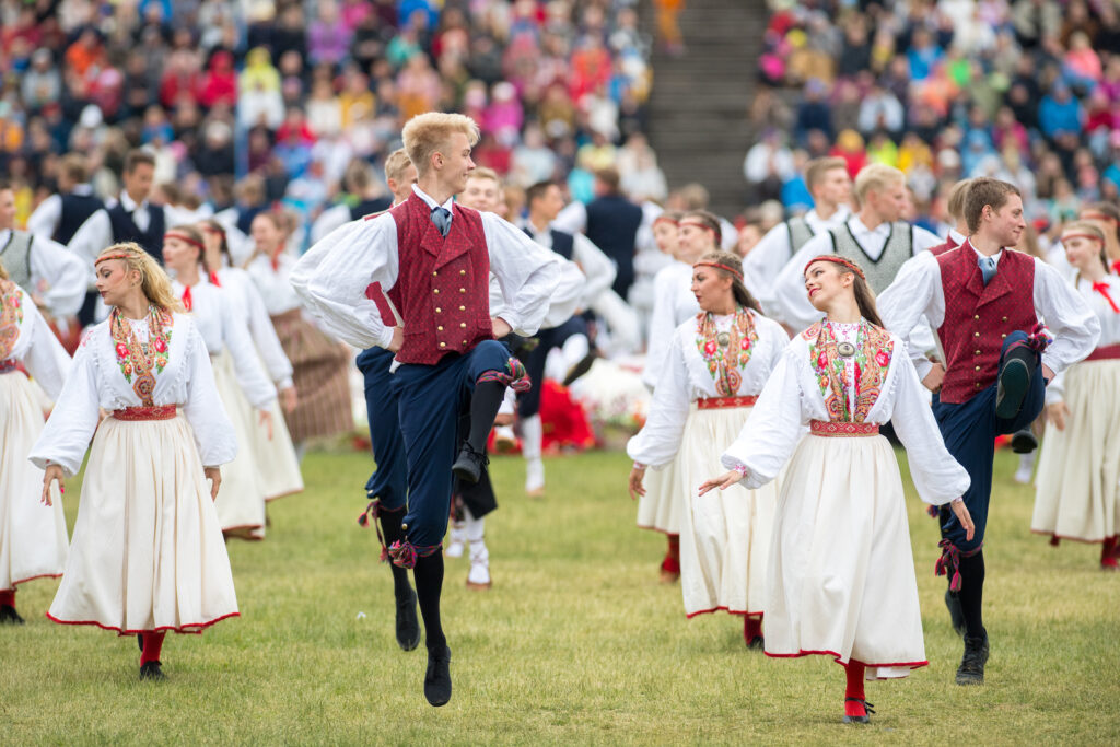 Kuvassa on nuorten tanssijuhlien tanssijoita tanssimassa kansallispuvuissa.