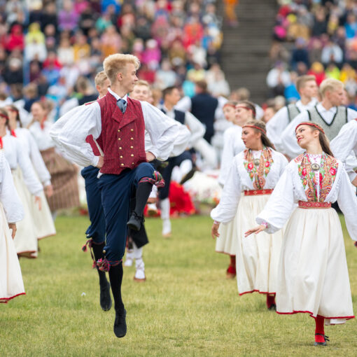 Kuvassa on nuorten tanssijuhlien tanssijoita tanssimassa kansallispuvuissa.